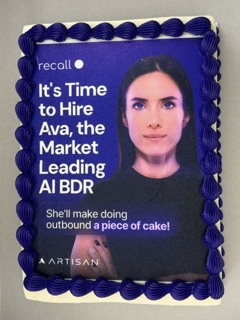 A top-down view of a sheet cake printed with an AI-generated woman and the copy "It's time to hire Ava, the market leading AI BDR. She'll make doing outbound a piece of cake!"