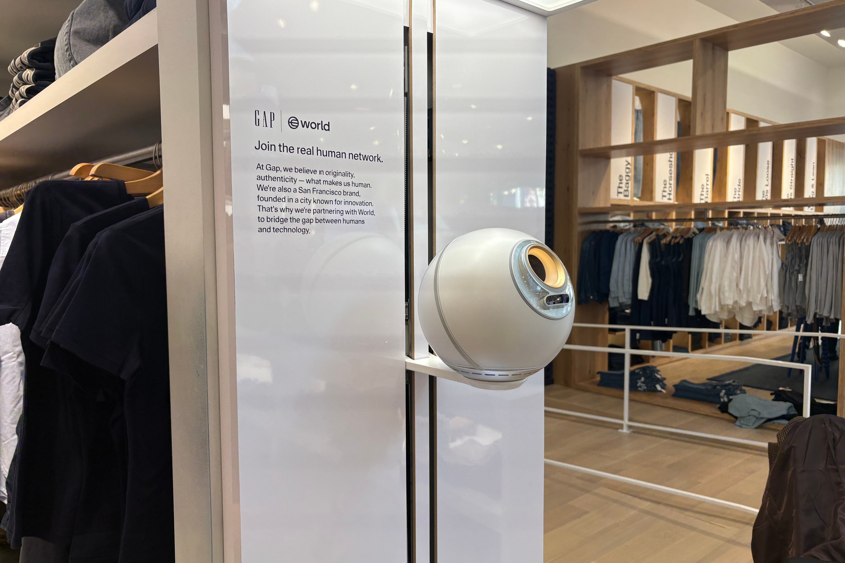 A white sphere attached to a wall inside a Gap store. The plaque beside the sphere reads "Join the real human network."