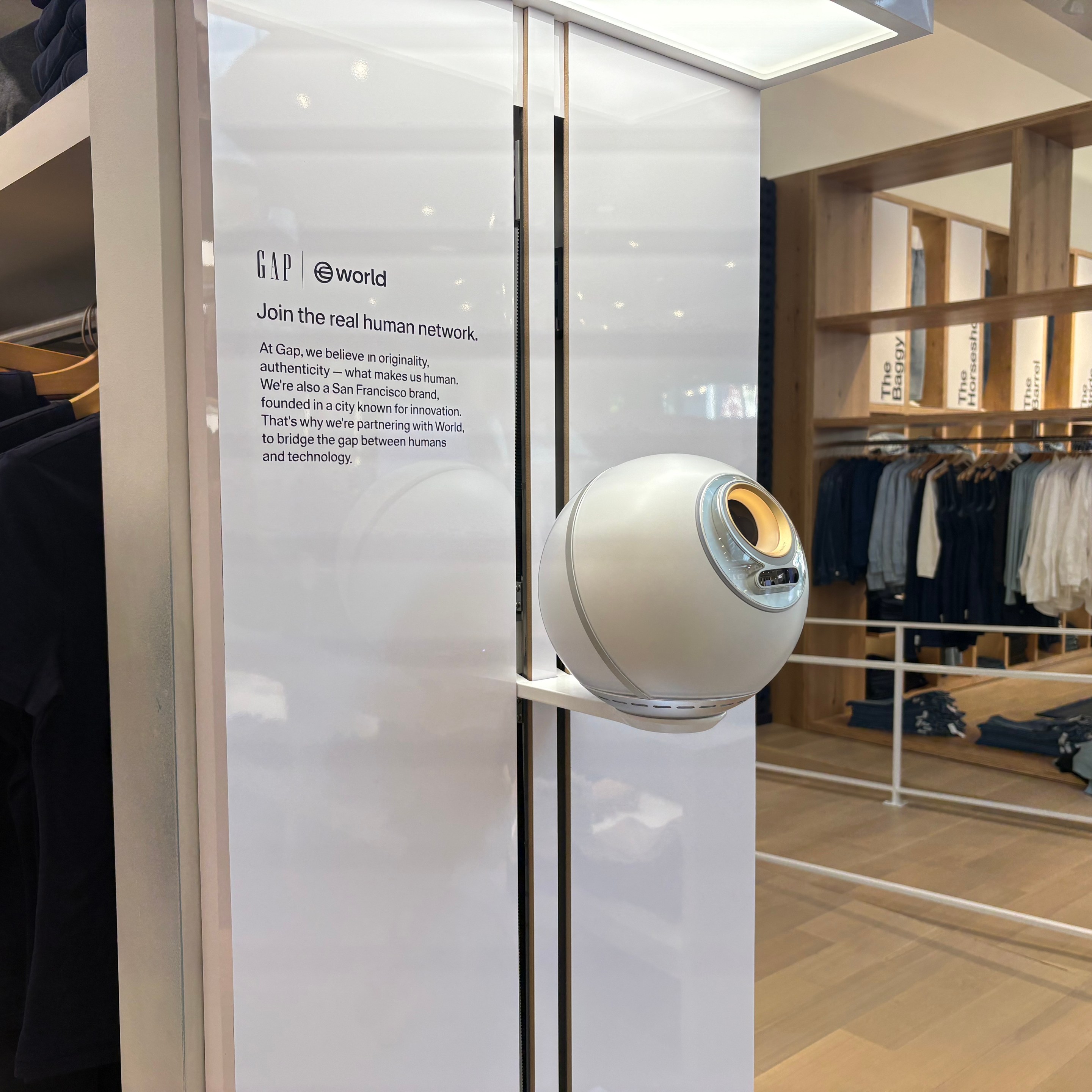 A white sphere attached to a wall inside a Gap store. The plaque beside the sphere reads "Join the real human network."