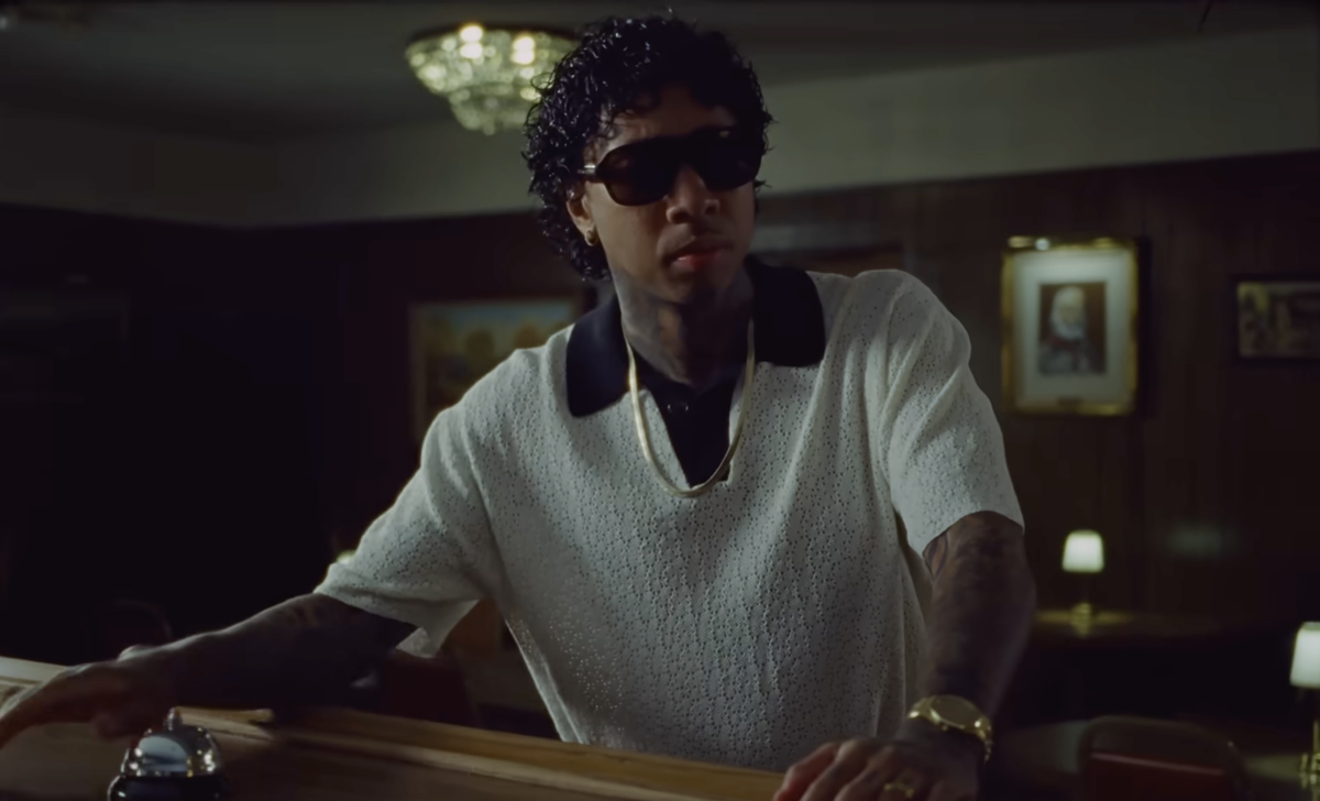 Man wearing dark sunglasses and white shirt indoors with casual confident pose