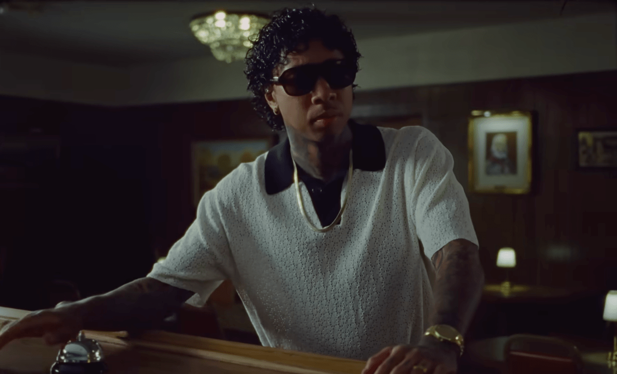 Man wearing dark sunglasses and white shirt indoors with casual confident pose