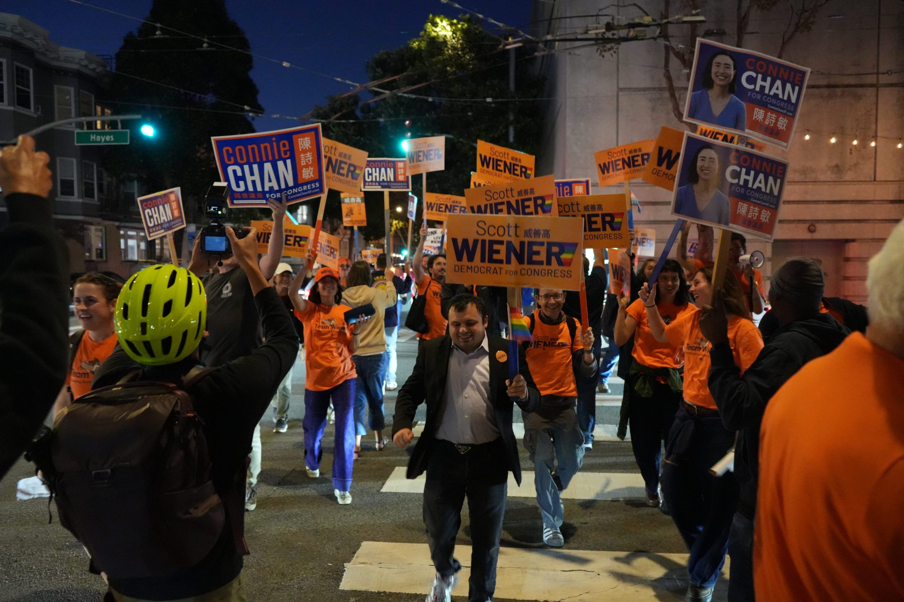 Crowd of supporters holding campaign signs for Wiener and Chan at a nighttime political rally.