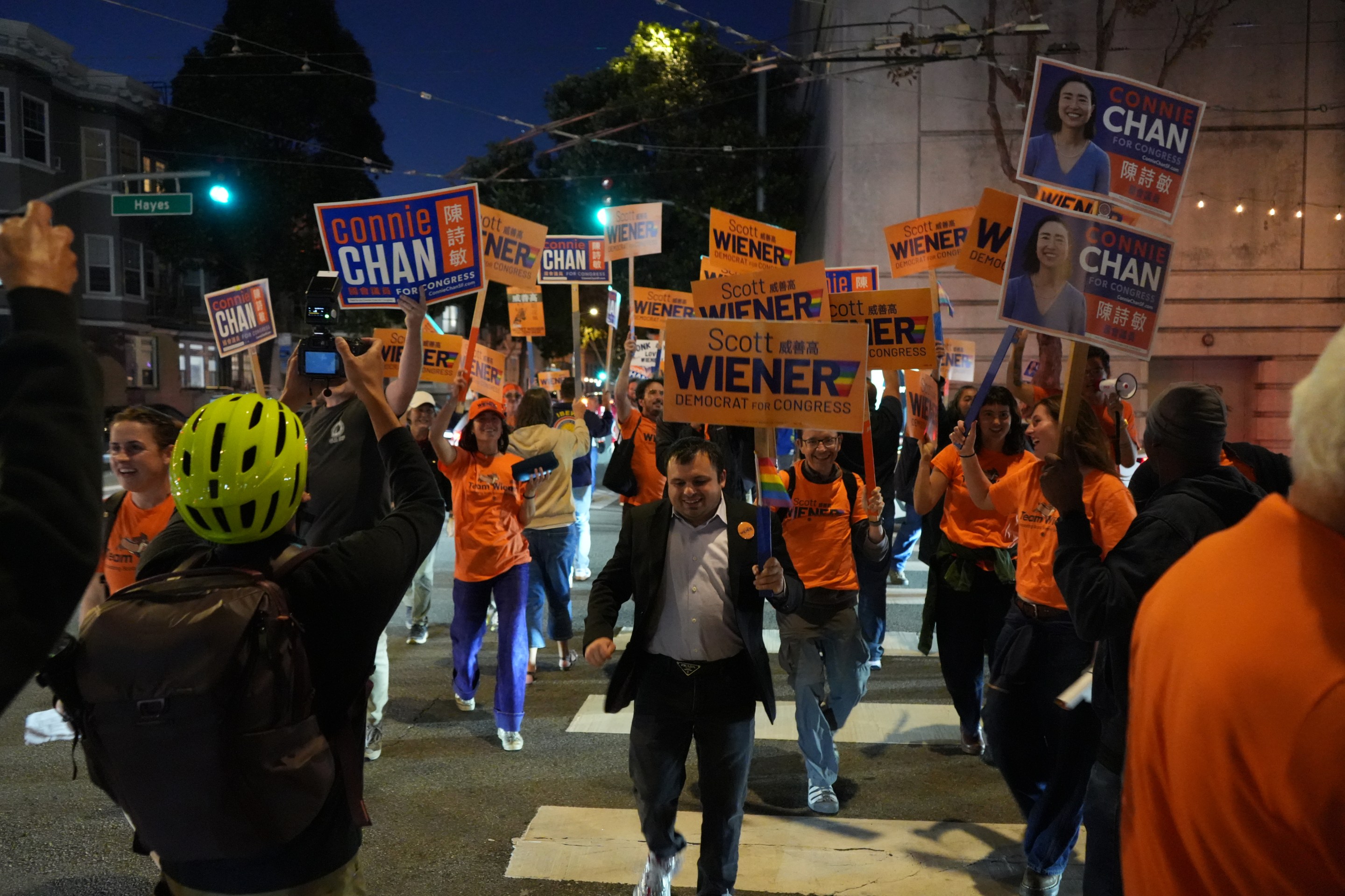 Crowd of supporters holding campaign signs for Wiener and Chan at a nighttime political rally.