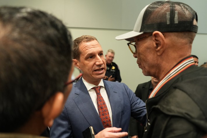 Formal meeting with professional man in blazer conversing with person wearing military ribbon.