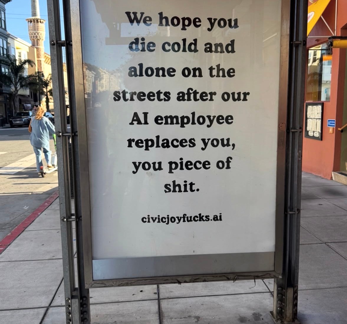 Protest sign in bus shelter criticizing AI job replacement with aggressive messaging