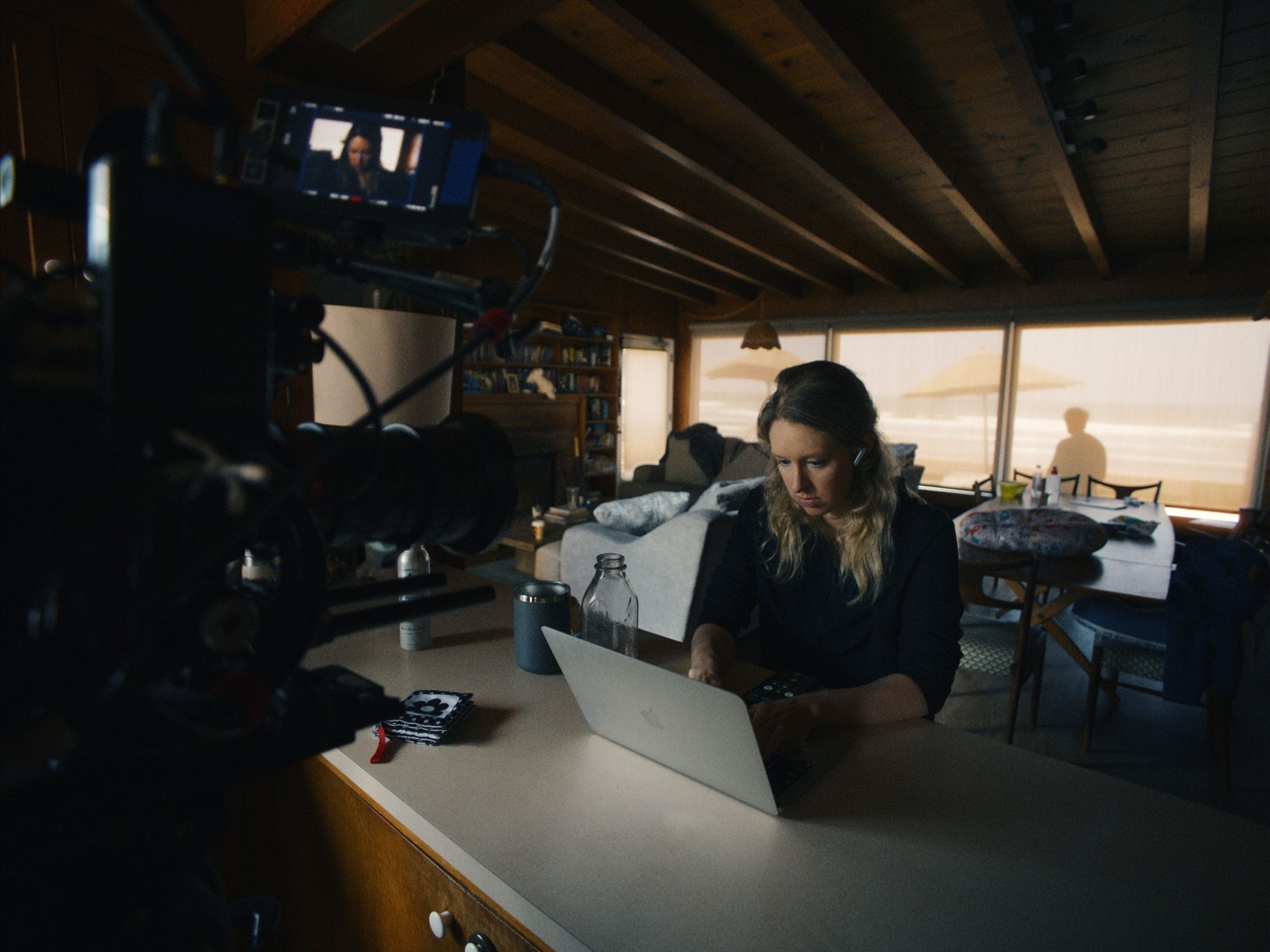 Woman working on laptop during film production with camera and crew on set