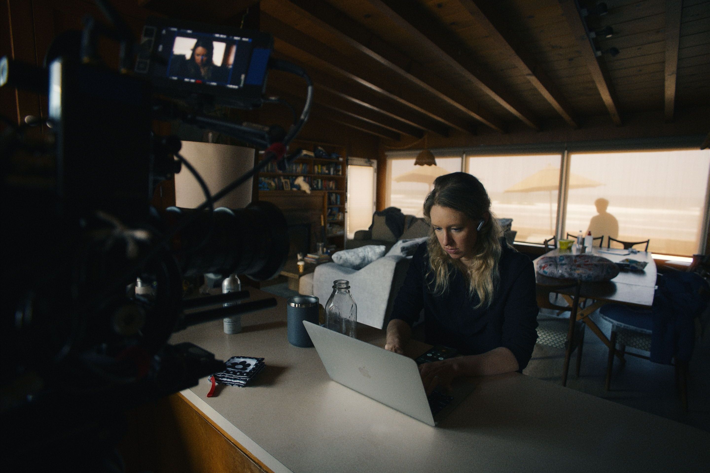 Woman working on laptop during film production with camera and crew on set